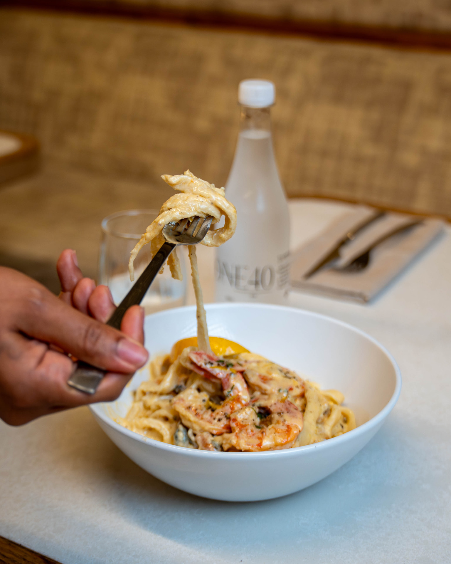 Creamy prawn pasta being lifted from the bowl at ONE40vue